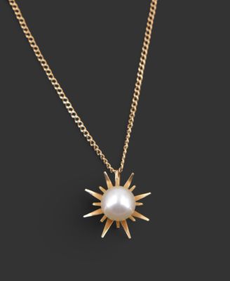 un collier en or avec un pendentif en forme de perle blanche, monté sur une chaîne en or