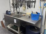 a kitchen with a sink and a counter with a bunch of utensils on it