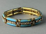 a close up of a gold and turquoise bracelet on a gray surface