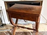 une petite table en bois munie d'un tiroir, placée devant une cheminée