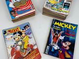 three mickey mouse comic books sitting on top of a white table