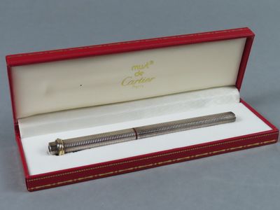 l'image d'un stylo dans une boîte rouge posée sur une surface grise