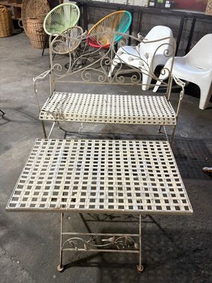 un banc en fer blanc avec deux chaises et une table