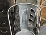 plusieurs chaises en métal et une chaise dans une pièce, à côté d'une commode