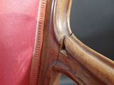 the back of a wooden chair with a red cushion on it