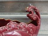 a red vase with a bird decoration on it