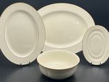 four pieces of white and gold dinnerware on a table