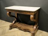 an old wooden table with a marble top on top of a wooden floor