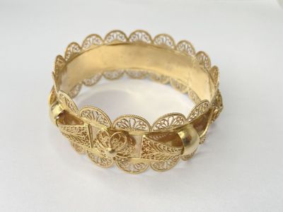 an image of a close up of a gold bracelet on a white surface