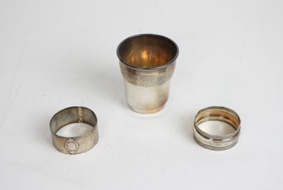 deux coupes en argent et une bague en argent posées sur une surface blanche