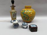 un vase jaune, un vase bleu et blanc et une lampe noire posés sur une table blanche