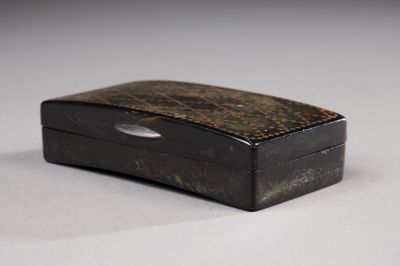 une petite boîte noire munie d'une poignée en métal, posée sur une table