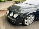 a black bentley car parked on the side of the road