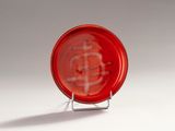 a red glass plate with a red and white design on it