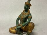 statue représentant une personne assise sur un morceau de bois, coiffée d'un chapeau