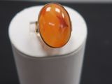 une bague en pierre orange posée sur une boîte blanche