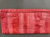 a red snake skin purse on a gray surface