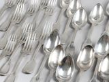 a lot of silver spoons and forks laid out on a table