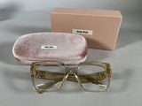 des lunettes dans un étui rose et une boîte rose posés sur une table