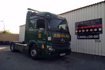 un semi-remorque vert garé devant un immeuble