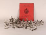 des figurines en argent représentant des soldats et un livre rouge posés sur une surface blanche
