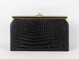 une pochette en cuir de crocodile noir avec un fermoir doré