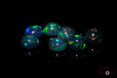 quelques perles d'oplite vertes et bleues sont disposées sur un fond noir