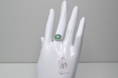 une image représentant une main blanche avec une bague verte au doigt