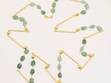 a set of green and gold necklaces on a white surface