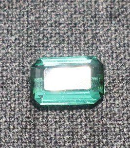 un gros plan d'une émeraude verte sur une surface grise