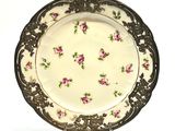 une assiette blanche ornée de fleurs roses, posée sur un socle