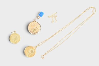 three gold necklaces and a coin on a white surface