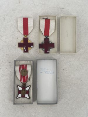three medals and a card in a box on a white surface