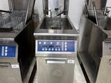 four commercial fryers are lined up in a row in a kitchen