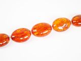 une rangée de perles de verre orange sur un fond blanc