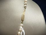 pearl and gold necklace on mannequin neck with feather charm