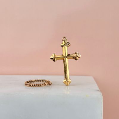 une bague en forme de croix en or posée sur un bloc de marbre