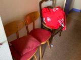 un sac rouge posé sur une chaise, à côté de deux autres chaises