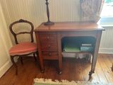 a desk with a chair and a lamp in the corner