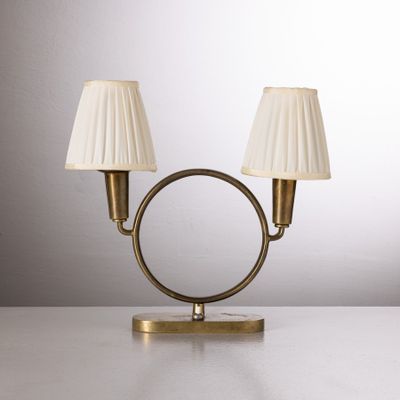une paire de lampes de table en laiton avec des abat-jours blancs, posées sur une surface blanche