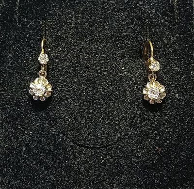 une paire de boucles d'oreilles en or et diamants sur une surface noire