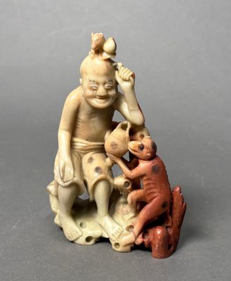 a figurine of a man sitting on a rock with a monkey