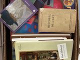 une boîte remplie de livres posée par terre à côté d'un ordinateur portable