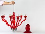a woman standing next to a red chandelier and a red candle holder