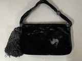 a black purse with a tassel hanging on a wall