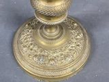 a gold candle holder on a table with a blue background