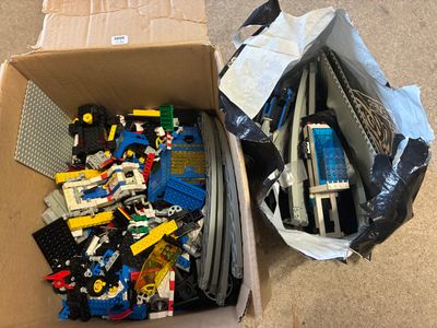 une boîte remplie de Lego posée par terre à côté d'un carton
