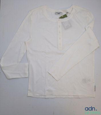 La chemise est blanche et comporte des boutons au niveau du col.