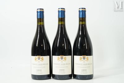 trois bouteilles de vin rouge sont posées sur une surface blanche