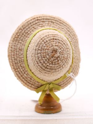 un chapeau de paille orné d'un ruban vert, posé sur un support en bois